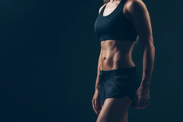 Портрет спортивной женщины в черной спортивной одежде в темноте — стоковое фото