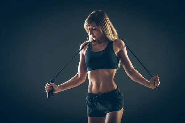 Deporte, actividad. Mujer linda con saltar la cuerda. Muscular chica negro fondo . —  Fotos de Stock
