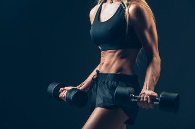 koyu arka plan üzerinde dumbbells ile atletik kadın
