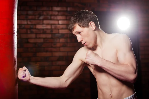 Muscular handsome fighter giving a forceful forward kick during  practise round with  boxing bag, kickboxing — Stock Photo, Image