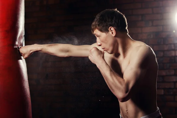 Muskulös stilig fighter ger en kraftfull framåt kick under praktiken runt med boxning väska, kickboxning — Stockfoto