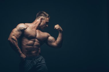 siyah arka plan üzerinde poz yakışıklı kaslı vücut geliştirmeci.