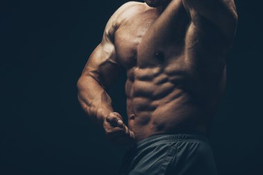 siyah arka plan üzerinde poz yakışıklı kaslı vücut geliştirmeci.