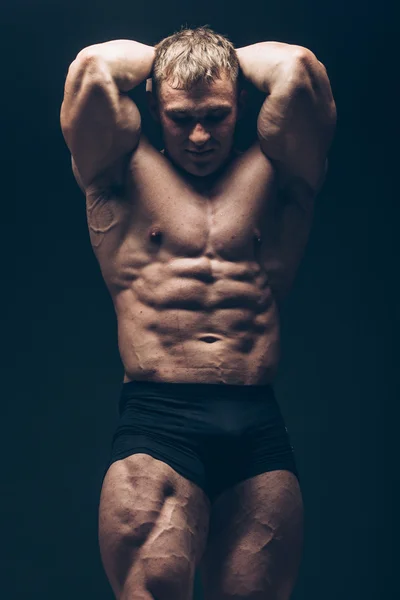 Knappe gespierde bodybuilder poseren op zwarte achtergrond. — Stockfoto