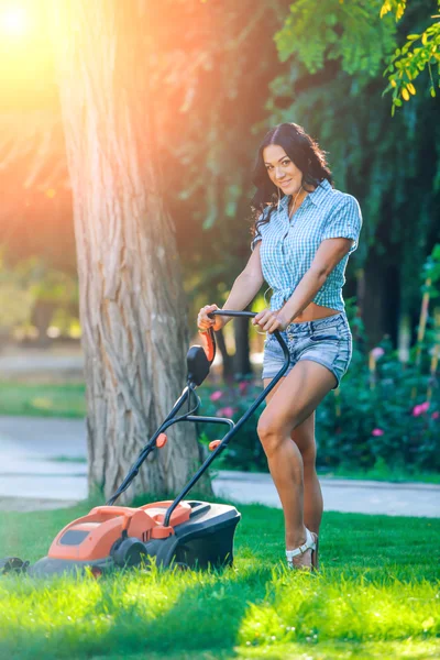 Woman mowing lawn in residential back garden on sunny day — 图库照片