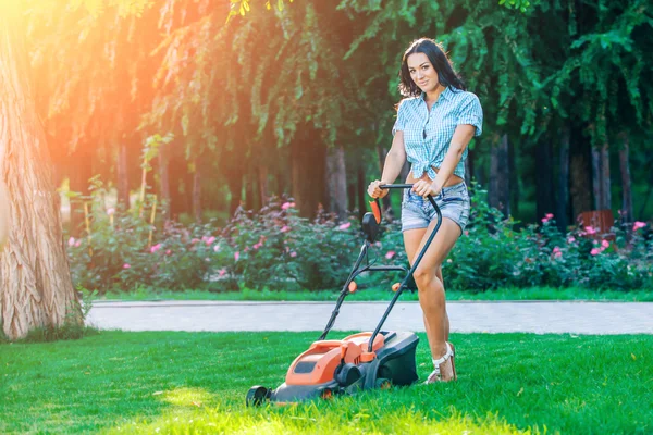 Woman mowing lawn in residential back garden on sunny day — 스톡 사진