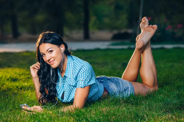 Relaxed woman lying on grass listening to music — Stock Photo, Image