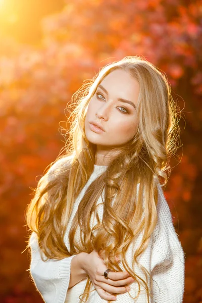 Mujer joven sobre un fondo de hojas de otoño rojas y amarillas con hermoso pelo rizado — Foto de Stock