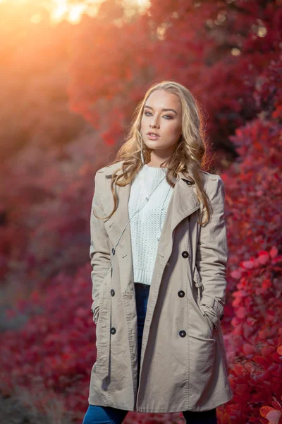 Νεαρή γυναίκα σε φόντο κόκκινο και κίτρινο το φθινόπωρο αφήνει με όμορφα σγουρά μαλλιά — Φωτογραφία Αρχείου