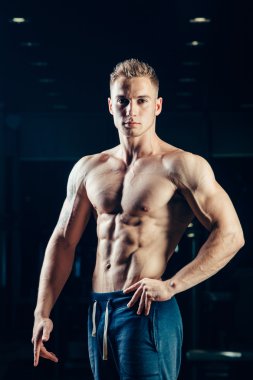 Bir atlet silüeti. Kendine güvenen genç fitness adam güçlü elleri olan. Dramatik ışık.