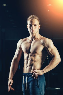 Bir atlet silüeti. Kendine güvenen genç fitness adam güçlü elleri olan. Dramatik ışık.