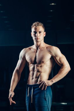 Bir atlet silüeti. Kendine güvenen genç fitness adam güçlü elleri olan. Dramatik ışık.