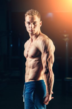 Bir atlet silüeti. Kendine güvenen genç fitness adam güçlü elleri olan. Dramatik ışık.