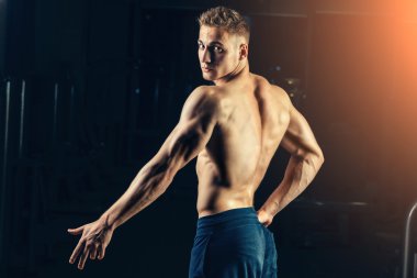 Bir atlet silüeti. Kendine güvenen genç fitness adam güçlü elleri olan. Dramatik ışık.