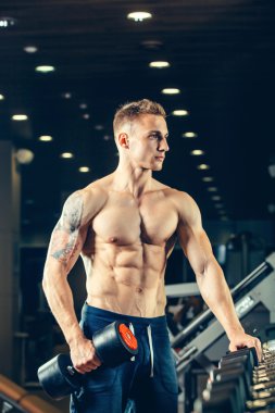 Male athlete with a dumbbell in the gym lean on row