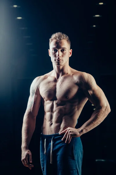 La silueta de un atleta. Joven hombre de fitness seguro con manos fuertes. Luz dramática . —  Fotos de Stock