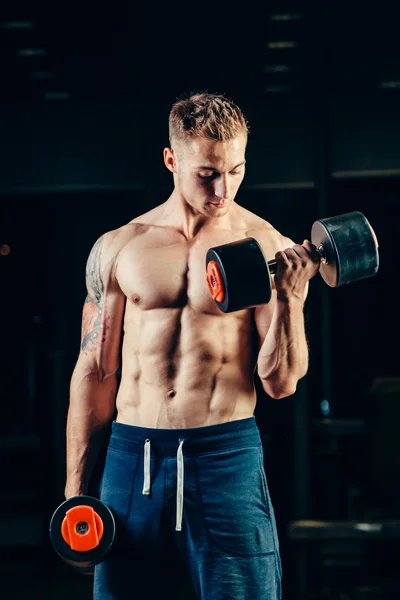 Idrottsman muskulös bodybuilder utbildning tillbaka med hantel på gymmet — Stockfoto