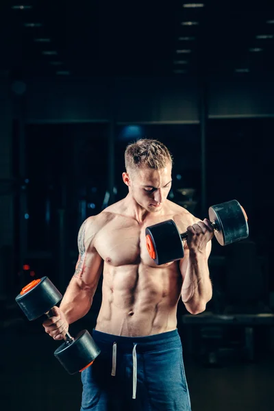 Athlete muscular bodybuilder training back with dumbbell  in the gym — Stock Photo, Image
