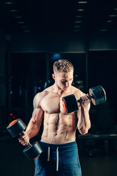 Atleta musculoso culturista entrenamiento de nuevo con mancuerna en el gimnasio —  Fotos de Stock