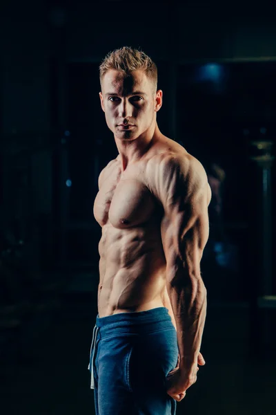 La silueta de un atleta. Joven hombre de fitness seguro con manos fuertes. Luz dramática . —  Fotos de Stock