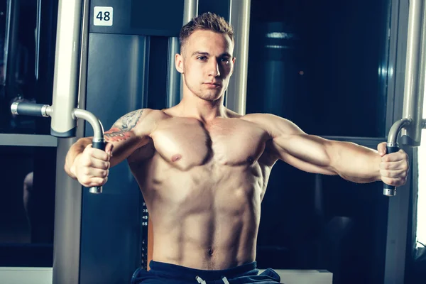 Brutal athletic man pumping up muscles on crossover — Stock Photo, Image