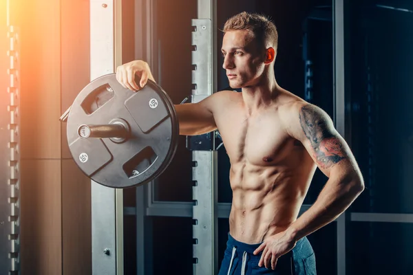 Closeup portrait of a muscular man workout with barbell at gym. Brutal bodybuilder athletic six pack, perfect abs, shoulders, biceps, triceps and chest — Stok fotoğraf