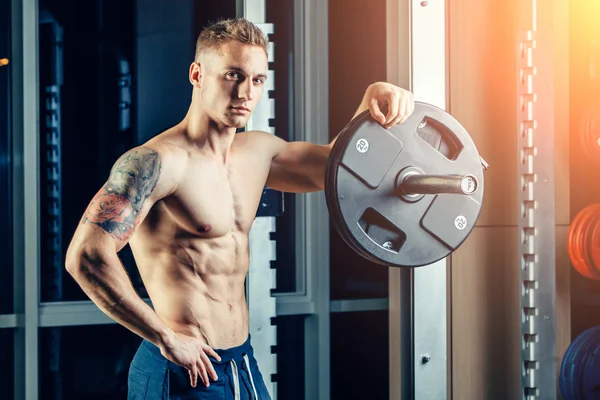 Closeup portrait of a muscular man workout with barbell at gym. Brutal bodybuilder athletic six pack, perfect abs, shoulders, biceps, triceps and chest — Stok fotoğraf