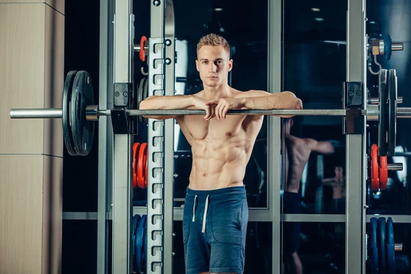 Retrato de cerca de un entrenamiento de hombre musculoso con barra de pesas en el gimnasio. Brutal culturista atlético pack de seis, abdominales perfectos, hombros, bíceps, tríceps y pecho —  Fotos de Stock