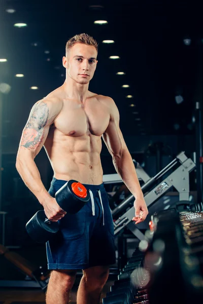 Athlète masculin avec un haltère dans la salle de gym maigre sur la rangée — Photo