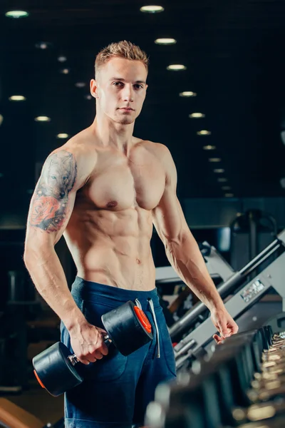 Male athlete with a dumbbell in the gym lean on row — Zdjęcie stockowe