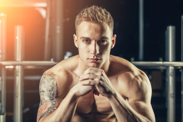 Closeup portrait of a muscular man workout with barbell at gym. He is sitting in the frame view, thinking — Stock Fotó