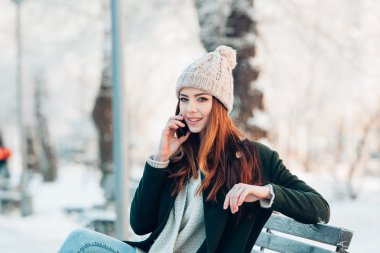 Akıllı telefon ve kış manzarası ile gülümseyen genç kadın .