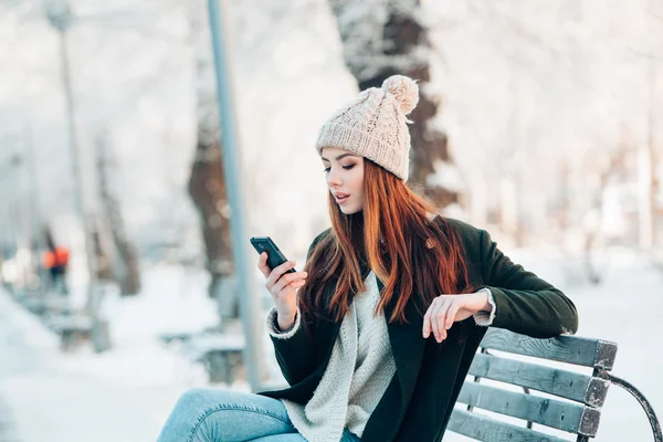 Fiatal nő, mosolygós, szúró telefon és a téli táj . — Stock Fotó