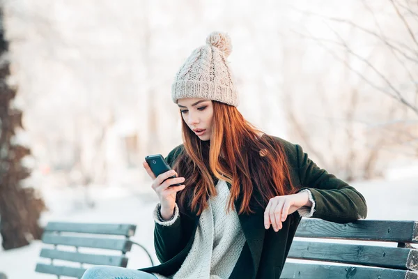 Jonge vrouw die lacht met slimme telefoon en winterlandschap . — Stockfoto