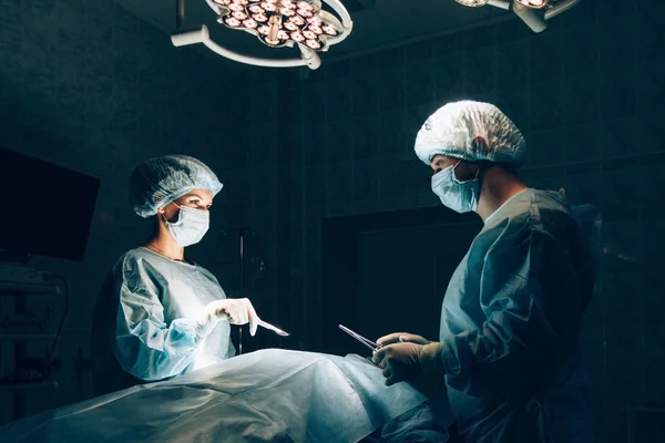 Equipo de cirujanos que trabaja con monitorización de pacientes en quirófano. Aumento de mamas . —  Fotos de Stock