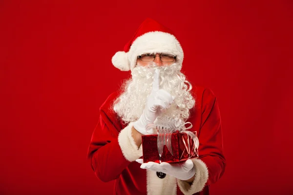 Photo of kind Santa Claus giving xmas present and looking at camera. secret hand lips. — Stock Photo, Image