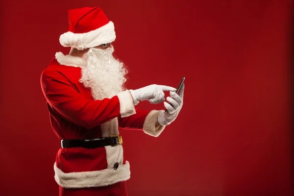 Moderní santa claus pomocí počítače tablet pc na červeném pozadí. Vánoční — ストック写真