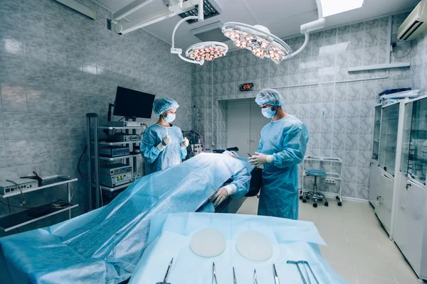 Χειρουργοί ομάδα εργασίας με παρακολούθηση του ασθενούς στη χειρουργική αίθουσα χειρουργείου. — Φωτογραφία Αρχείου