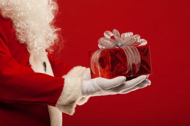 Photo of Santa Claus gloved hand with  giftbox, on a red background clipart