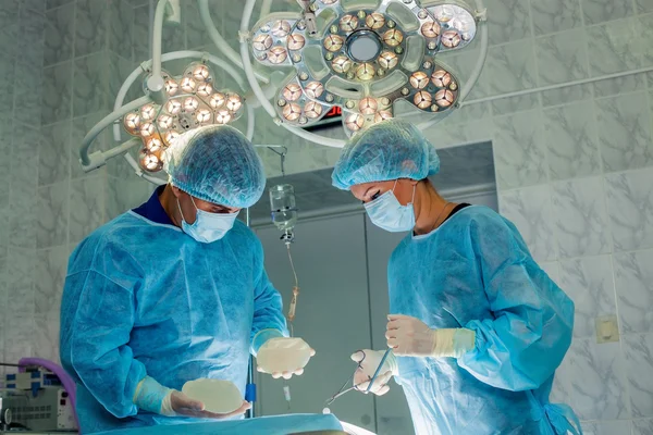 Команда хірургів, що працює з моніторингом пацієнта в хірургічній операційній. збільшення грудей — стокове фото