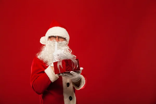 Foto einer Art Weihnachtsmann, der ein Weihnachtsgeschenk macht und in die Kamera schaut. Geheime Handlippen. — Stockfoto