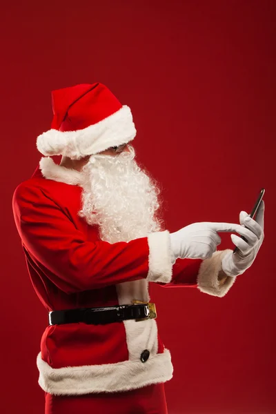 Moderní santa claus pomocí počítače tablet pc na červeném pozadí. Vánoční — ストック写真