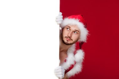 çok kaslı yakışıklı seksi Noel Baba kırmızı arka plan, tutun afiş ve gülümseme, izole bronzlaşmış