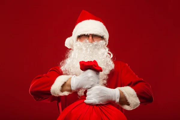 Santa claus with big bag on shoulder glasses  red background — Stock Photo, Image