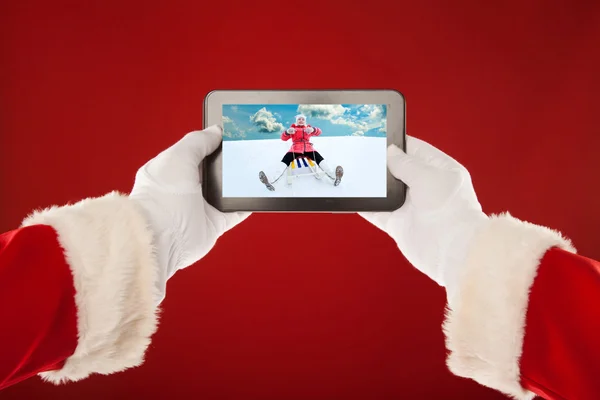 Santa Claus is holding  plate with  photo of a little girl sledding. Red background. — Stock Photo, Image