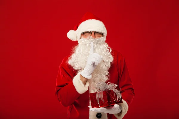 Photo du gentil Père Noël donnant cadeau de Noël et regardant la caméra. lèvres de main secrètes . — Photo