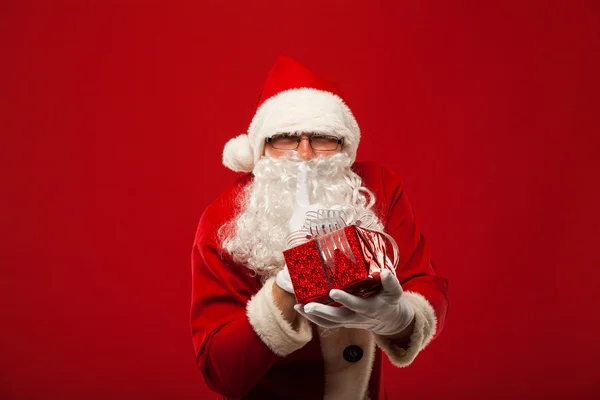 Photo du gentil Père Noël donnant cadeau de Noël et regardant la caméra. lèvres de main secrètes . — Photo