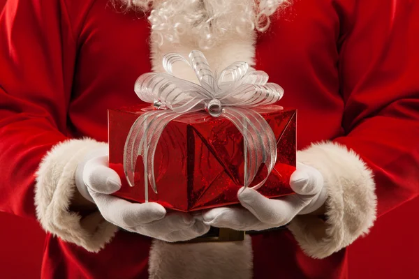 Foto de tipo Santa Claus dando regalo de Navidad y mirando a la cámara . —  Fotos de Stock