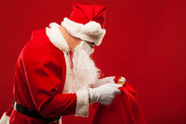 Santa claus avec gros sac sur épaule lunettes fond rouge — Photo
