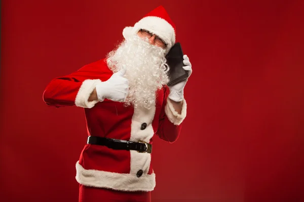 Glada jultomten talar i mobiltelefon och Visa okej gest. röda väggen bakgrunden. — Stockfoto